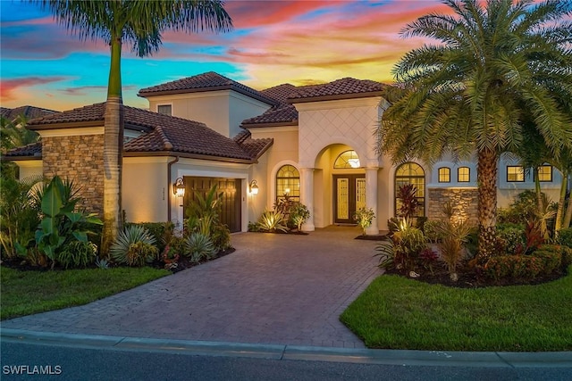 mediterranean / spanish home featuring a garage and a lawn