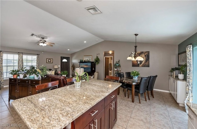 kitchen featuring light tile patterned floors, ceiling fan with notable chandelier, decorative light fixtures, and a kitchen island