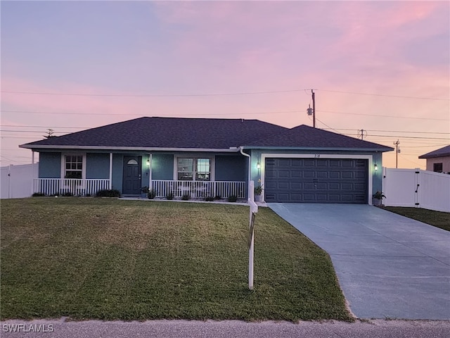 ranch-style house with covered porch, a garage, and a yard