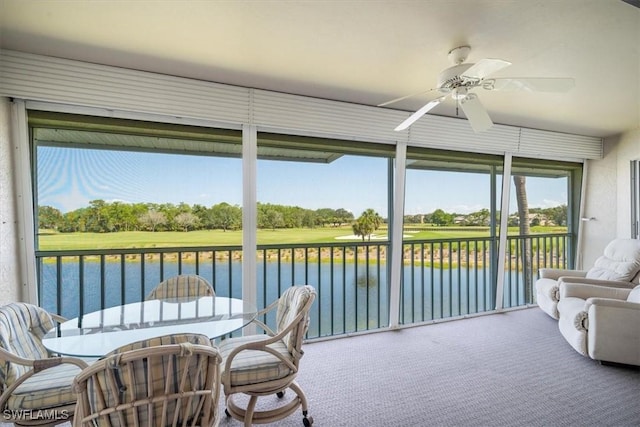 sunroom featuring ceiling fan and a water view