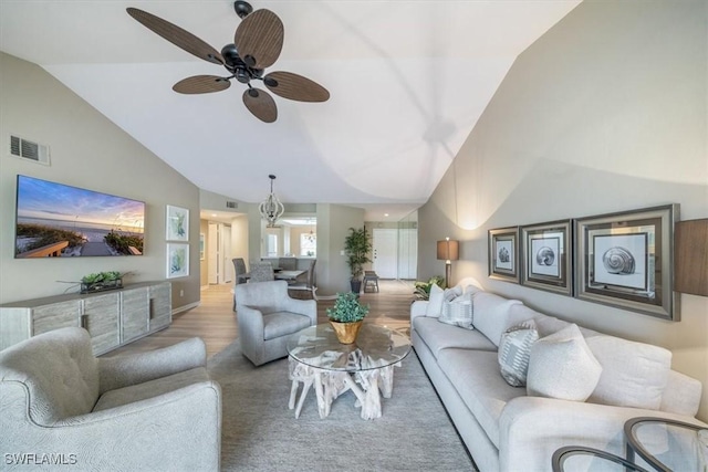 living room featuring ceiling fan with notable chandelier, light hardwood / wood-style floors, and lofted ceiling