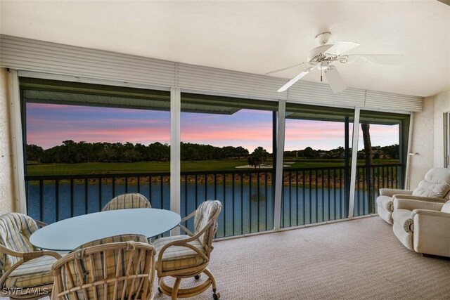 sunroom / solarium with ceiling fan and a water view