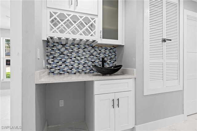 kitchen with sink, light stone counters, decorative backsplash, and white cabinetry