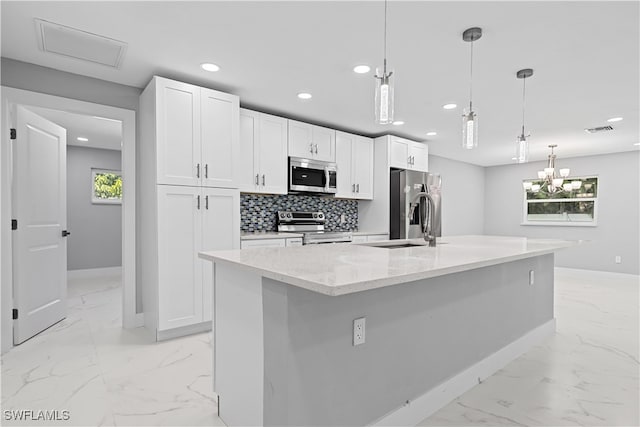 kitchen with a wealth of natural light, stainless steel appliances, an island with sink, and light tile patterned floors