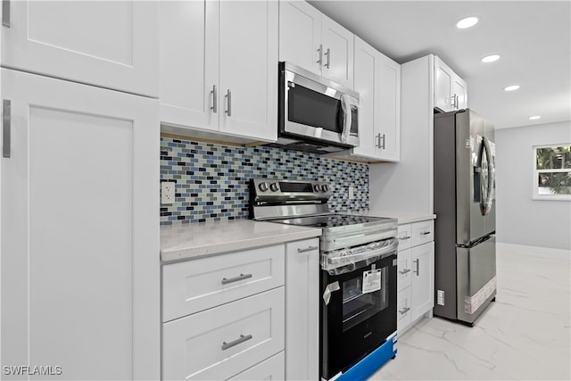 kitchen featuring decorative backsplash, white cabinetry, appliances with stainless steel finishes, light stone counters, and light tile patterned floors