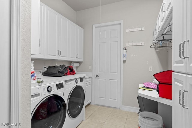 washroom featuring cabinet space, baseboards, washer and clothes dryer, and light tile patterned flooring