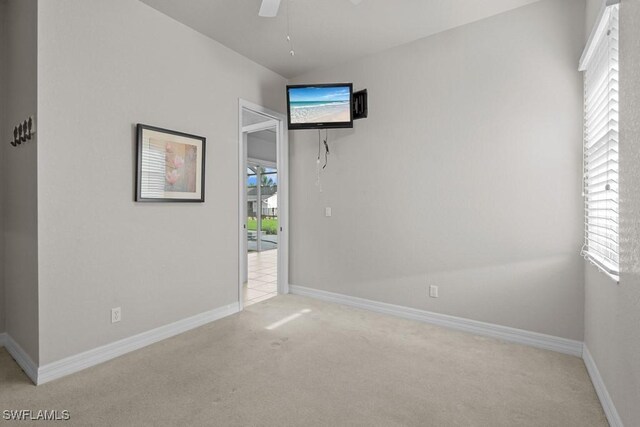 empty room featuring ceiling fan and light carpet