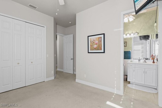 bedroom featuring a closet, visible vents, a sink, ensuite bath, and baseboards