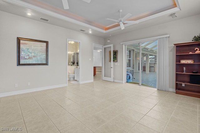 tiled empty room featuring a raised ceiling and ceiling fan