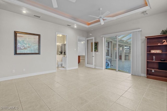 empty room with light tile patterned floors, visible vents, baseboards, a ceiling fan, and a tray ceiling