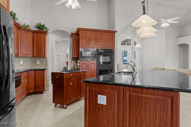 kitchen with ceiling fan, a kitchen island with sink, and stainless steel microwave