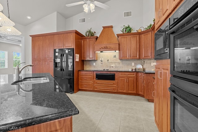 kitchen with dark stone countertops, black appliances, sink, ceiling fan, and custom range hood