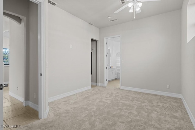 unfurnished bedroom with light carpet, baseboards, visible vents, and ensuite bathroom