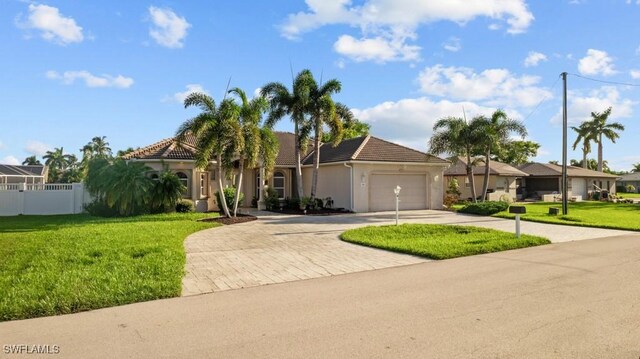 view of front of property with a tile roof, an attached garage, fence, decorative driveway, and a front lawn