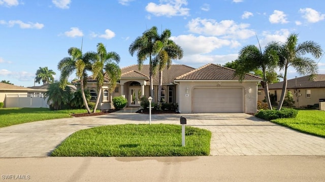 mediterranean / spanish-style home with a garage, a tile roof, decorative driveway, stucco siding, and a front yard