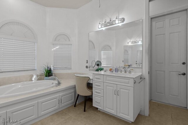 bathroom with tile patterned floors, a tub to relax in, and vanity