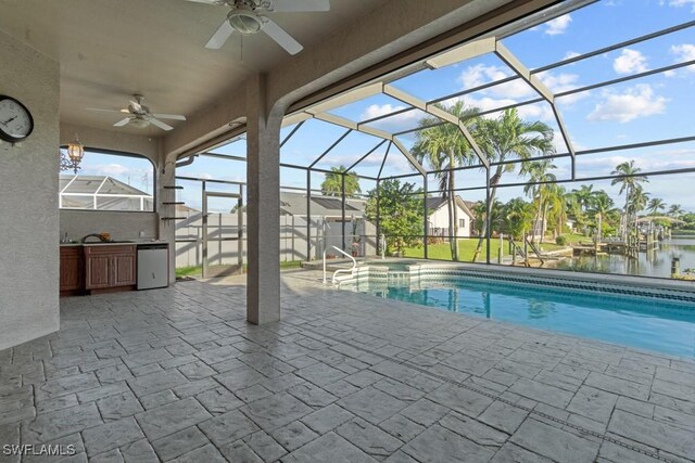 view of pool with a lanai, sink, a water view, ceiling fan, and a patio