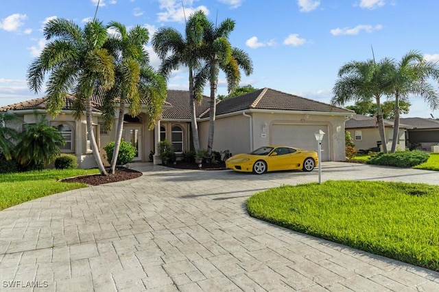 view of front of property featuring decorative driveway, a tile roof, stucco siding, an attached garage, and a front lawn