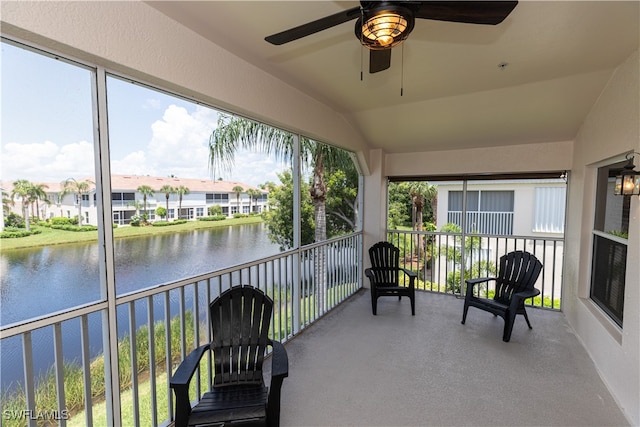 sunroom / solarium featuring ceiling fan, a water view, and vaulted ceiling