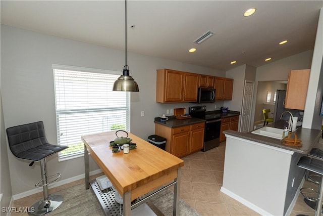 kitchen with light tile patterned floors, electric range, dark countertops, pendant lighting, and a sink