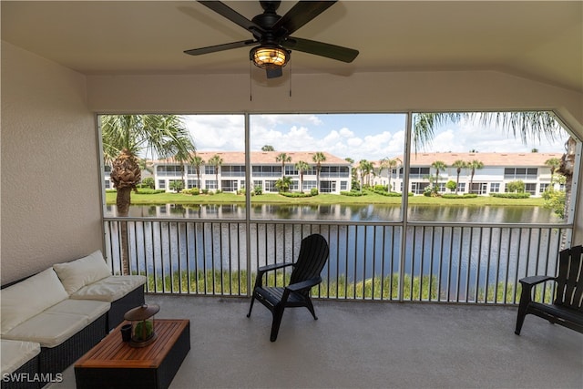 sunroom featuring ceiling fan and a water view