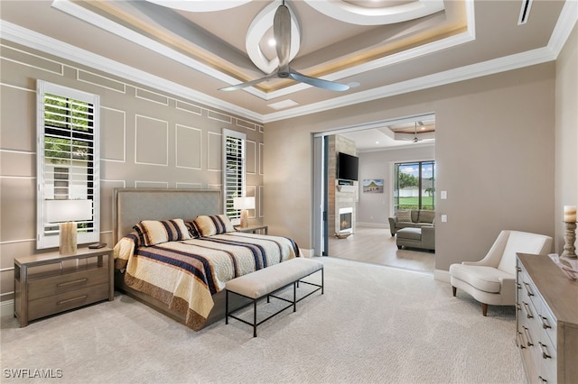 bedroom featuring ceiling fan, a raised ceiling, light colored carpet, and crown molding