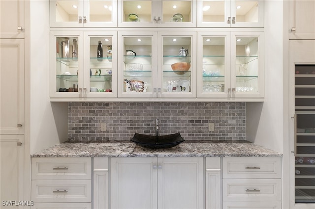 bar with white cabinetry and light stone counters