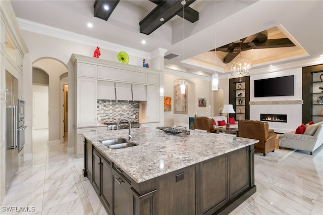 kitchen featuring tasteful backsplash, dark brown cabinetry, a tray ceiling, sink, and white cabinetry