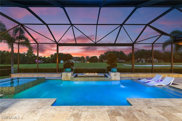 pool at dusk featuring an in ground hot tub, a patio, and a lanai