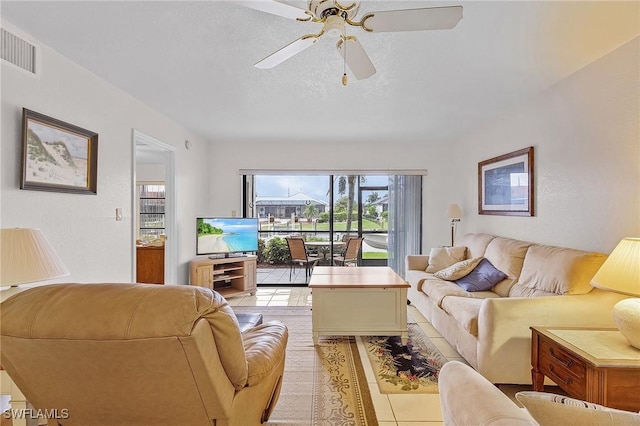 living room with a ceiling fan, visible vents, a textured ceiling, and light tile patterned flooring