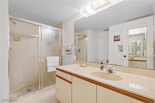 bathroom with a shower with door, a textured ceiling, vanity, and tile patterned flooring