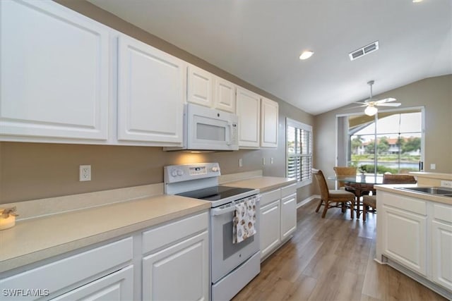 kitchen featuring white appliances, lofted ceiling, light wood-type flooring, white cabinets, and ceiling fan