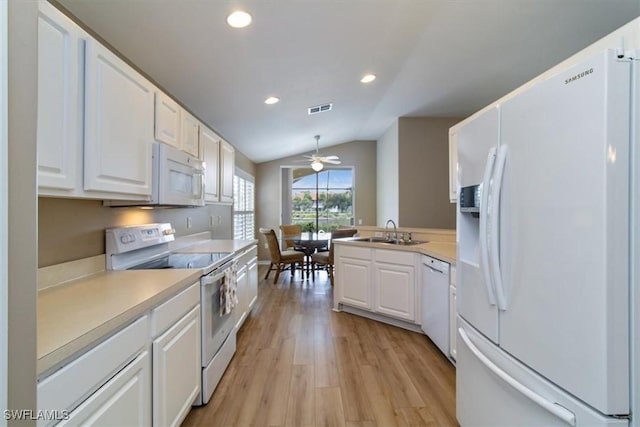 kitchen featuring white appliances, light wood-type flooring, white cabinets, lofted ceiling, and sink