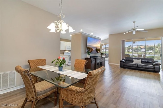 dining space featuring ceiling fan with notable chandelier and light hardwood / wood-style floors