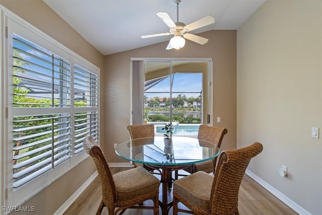 dining space featuring ceiling fan, light wood-type flooring, and vaulted ceiling