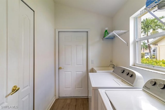 laundry room featuring sink, washer and clothes dryer, hardwood / wood-style flooring, and a wealth of natural light