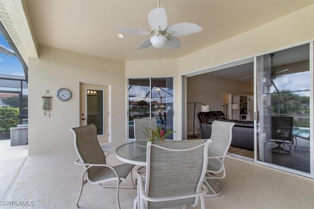 view of patio with ceiling fan and glass enclosure