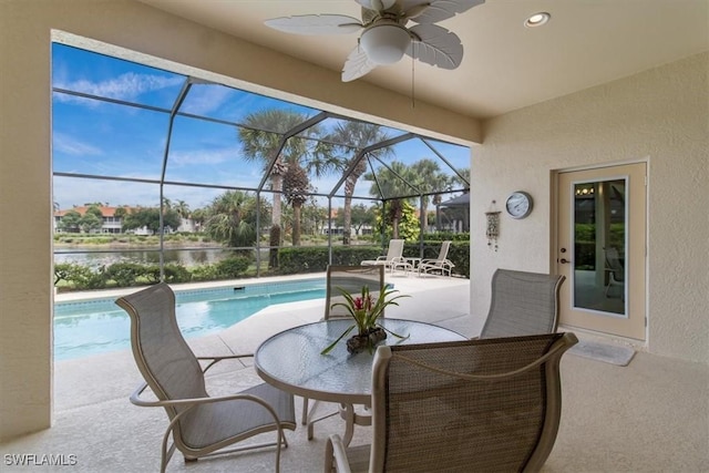 view of pool with ceiling fan, a lanai, a patio, and a water view