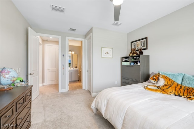 bedroom featuring ceiling fan, light colored carpet, and connected bathroom