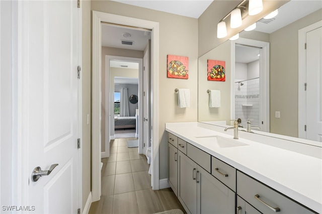 bathroom featuring tile patterned flooring, vanity, and a tile shower