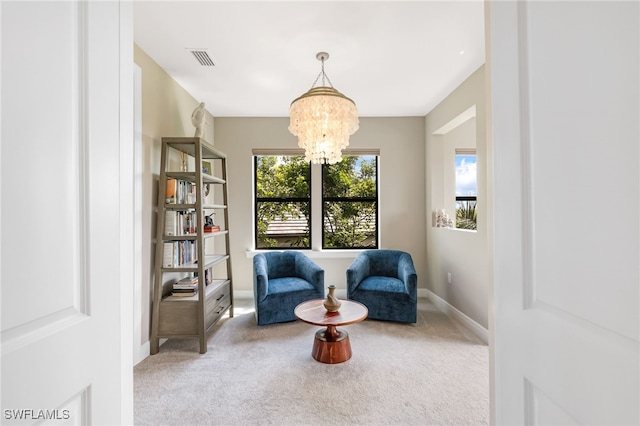 living area featuring light carpet and an inviting chandelier