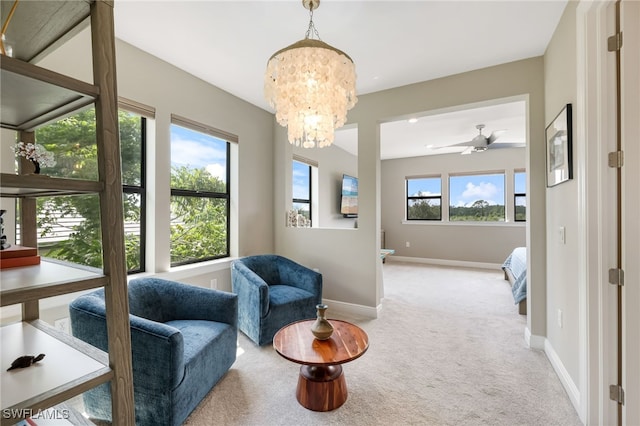 living area with ceiling fan with notable chandelier, a healthy amount of sunlight, and light carpet