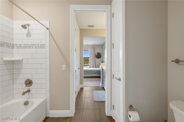 bathroom featuring tile patterned floors, toilet, and tiled shower / bath