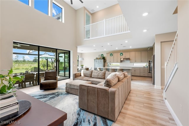 living room featuring light wood-type flooring and a towering ceiling