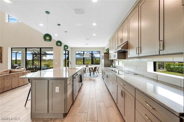 kitchen featuring an island with sink, light hardwood / wood-style floors, pendant lighting, extractor fan, and black electric stovetop