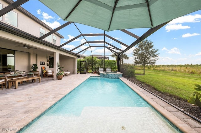 view of swimming pool with glass enclosure, ceiling fan, a patio, and an in ground hot tub