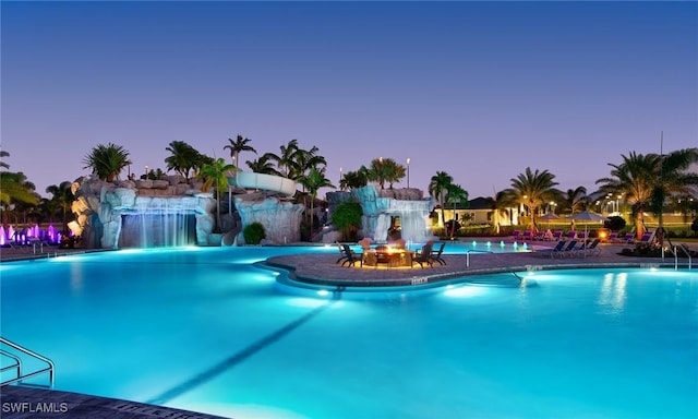 pool at dusk featuring pool water feature