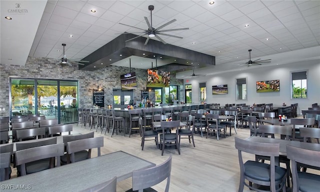 dining area featuring a paneled ceiling, light hardwood / wood-style flooring, and indoor bar