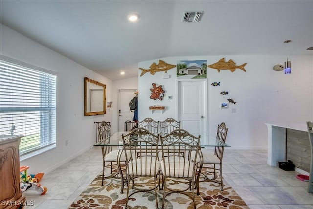 dining space with lofted ceiling, visible vents, baseboards, and light tile patterned flooring