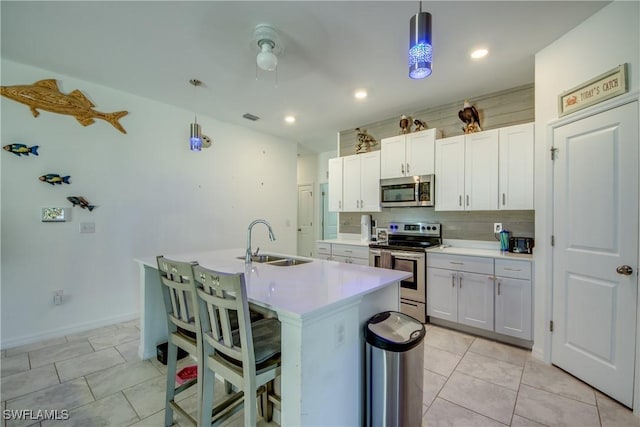 kitchen featuring appliances with stainless steel finishes, white cabinets, light countertops, and a sink